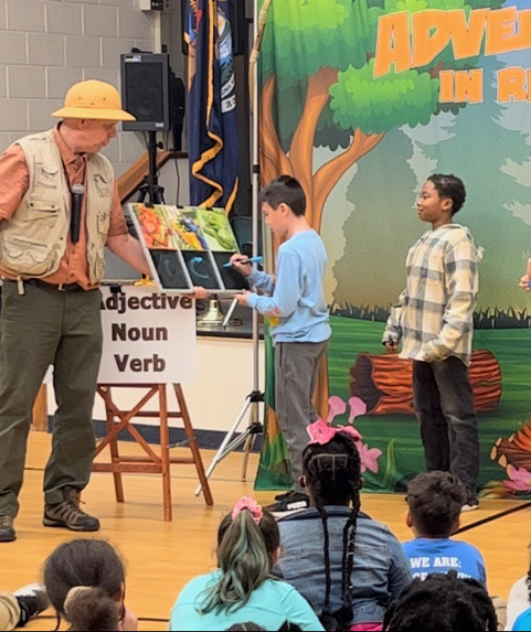 Students help create a story, live on stage, in our Adventures in Reading assembly show.