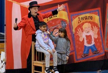 Doug Scheer presents an oversized story of Aesops Fable to teach respect during a Diversity Circus Assembly Show.