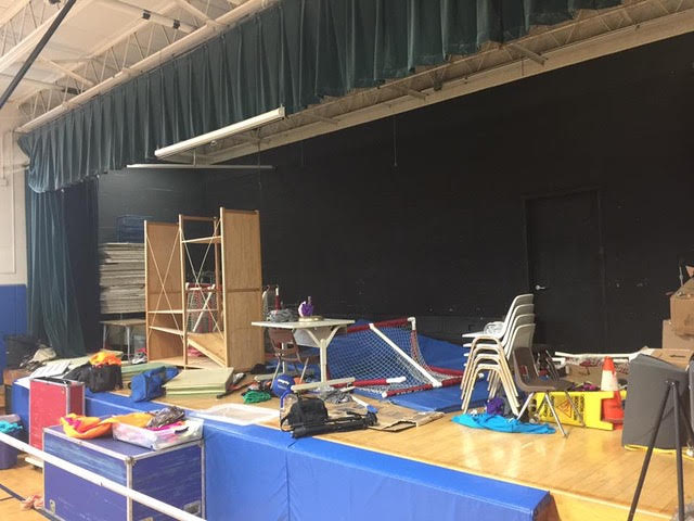 Sometimes the stage is not the best place for an assembly presentation. No custodian can be expected to move all this junk. 
